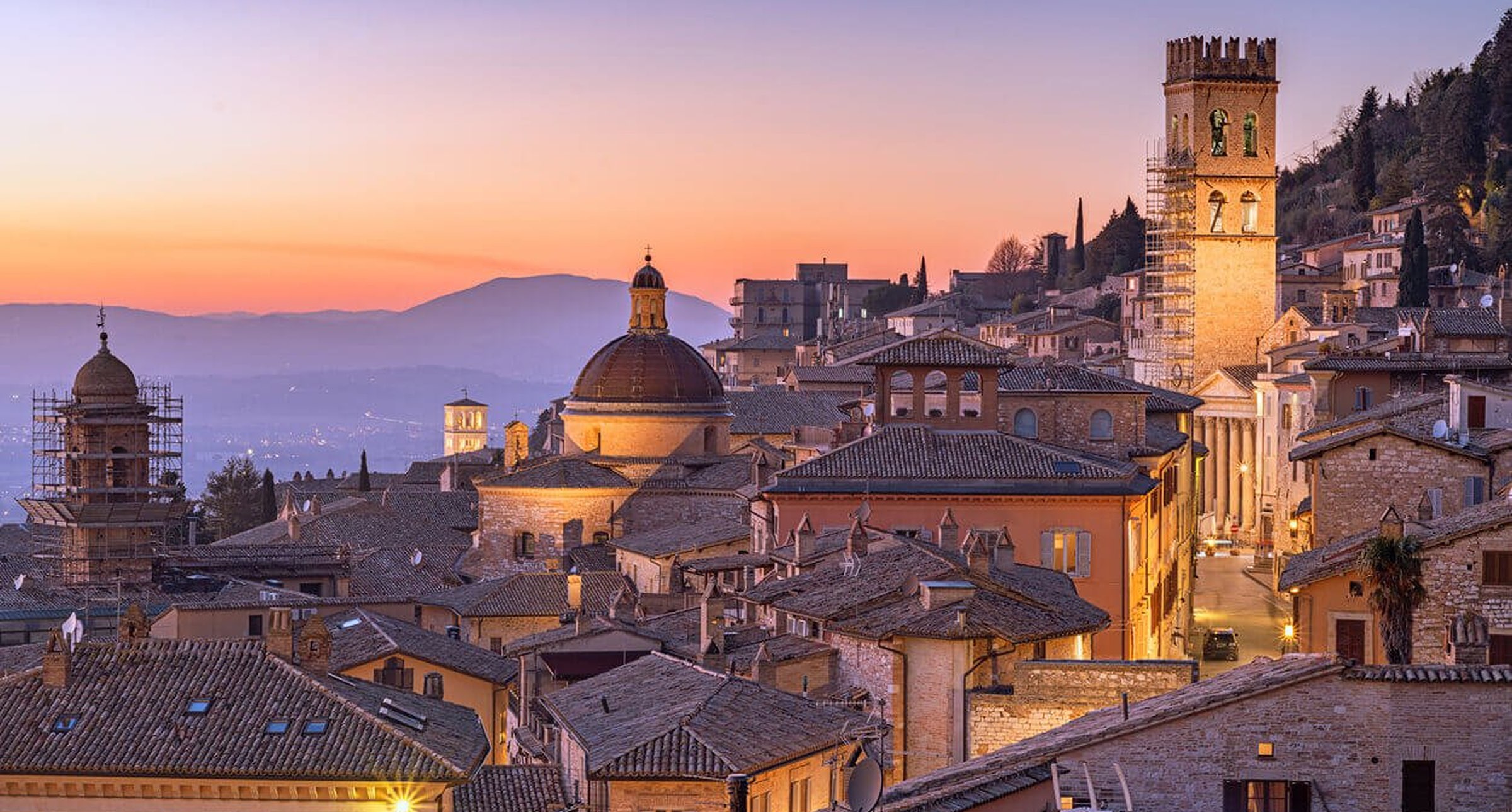 Historic European town with terracotta roofs and church domes at sunset